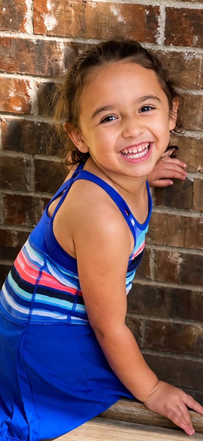 Smiling child portrait against a brick wall